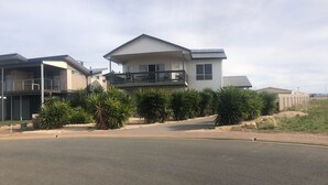 A two-story residential building with a balcony, surrounded by tropical plants and a paved driveway. - The White House ~ Free Wi-Fi, Arcade Machine - Off Peak Special! (Edithburgh)