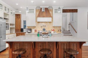 Een moderne keuken met een groot schiereiland, houten kastjes en hanglampen.