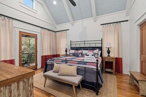 Een slaapkamer met een bed, een bankje, een nachtkastje en een raam met gordijnen.