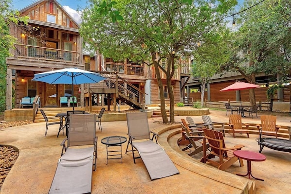 Une cabane en bois dotée d’un balcon, d’un espace extérieur aménagé avec des fauteuils et des tables, et d’un foyer.