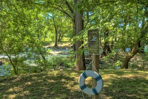 A lifebuoy attached to a wooden post with a sign indicating swimming at your own risk and lifeguard on duty.