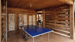 Una mesa de ping pong en una habitación rústica de madera con vigas a la vista y techo inclinado.