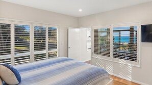 Quarto com cama, porta e janelas com persianas.