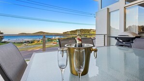 Un balcon avec une table, deux flûtes à champagne et une bouteille de champagne dans un seau à glace.