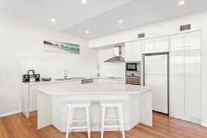 A modern kitchen with a central island, white cabinetry, and stainless steel appliances.