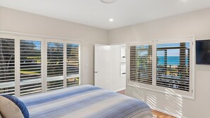 Une chambre à coucher avec un lit, une porte et des fenêtres équipées de stores.