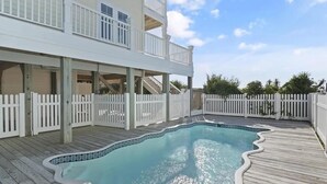 A two-story building with a swimming pool surrounded by a wooden deck and white picket fence. - Oceanfront retreat in Holden Beach, 4BR, 3BA, sleeps 10 with stunning views! (Holden Beach)