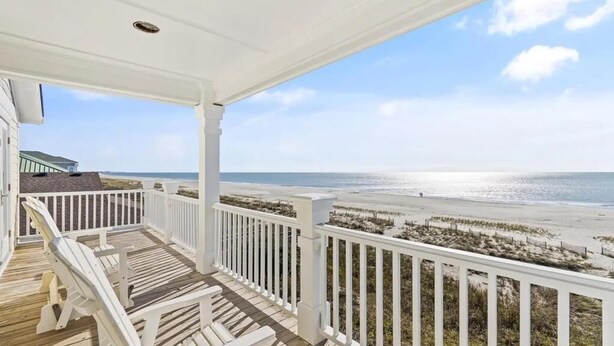 A covered porch with a view of the beach. - Oceanfront retreat in Holden Beach, 4BR, 3BA, sleeps 10 with stunning views! (Holden Beach)