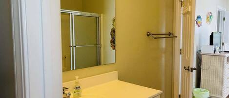 A bathroom with a white sink, a mirror, and a shower door.