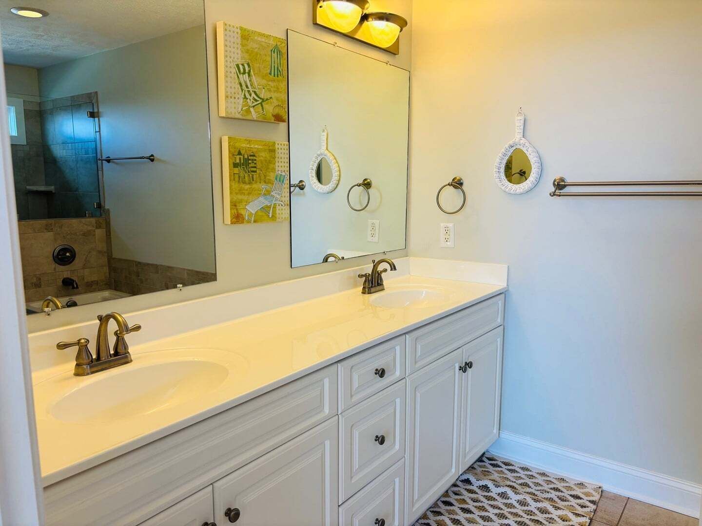 Un baño con tocador de doble lavabo, un espejo grande y dos toalleros de pared.