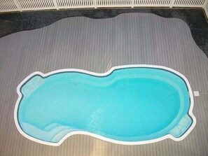 A swimming pool with a wooden deck surrounding it.