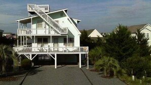 Una casa a più piani con una scala, un balcone e un vialetto.