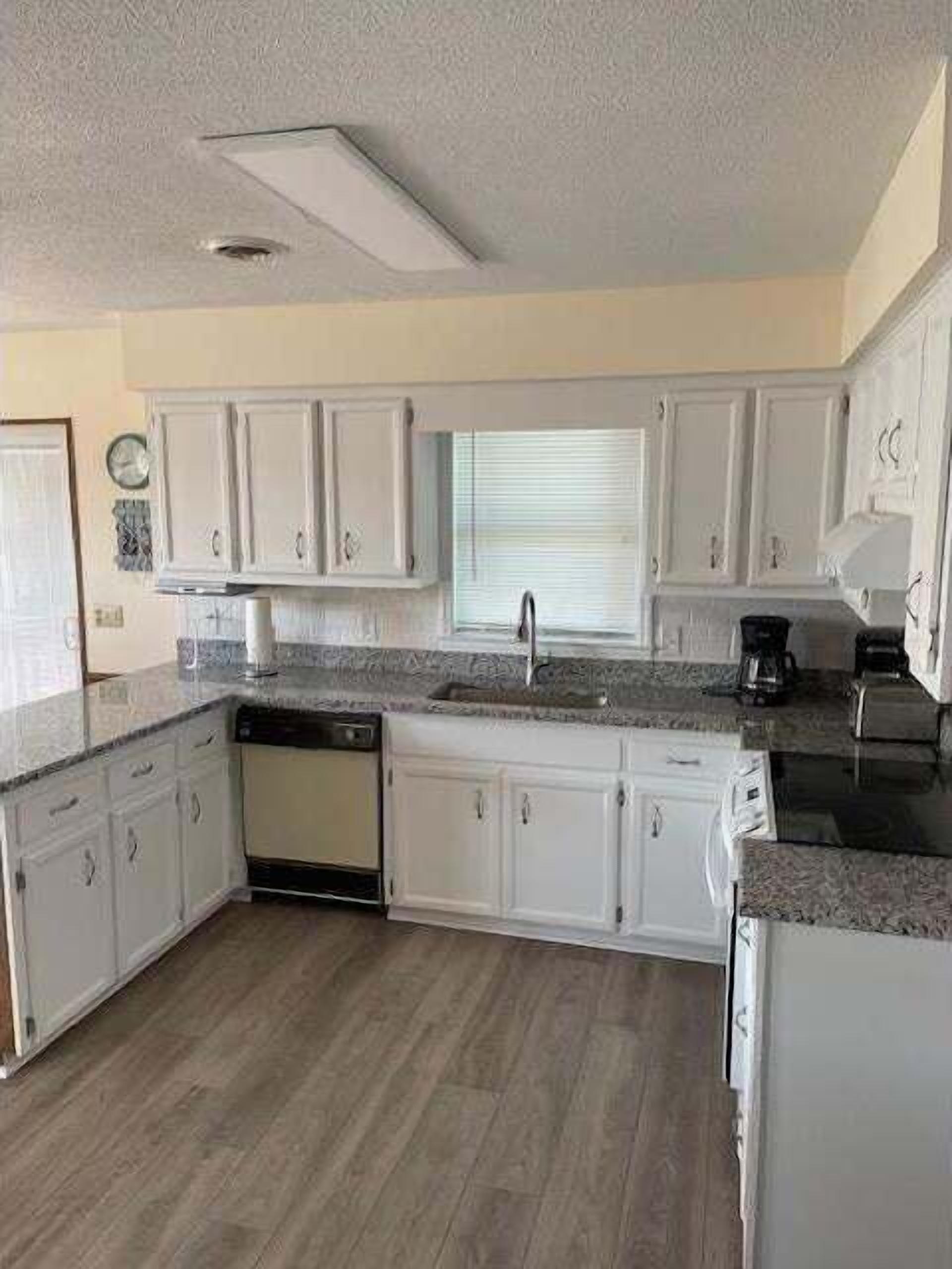 A kitchen with white cabinets, a dishwasher, and a coffee maker.