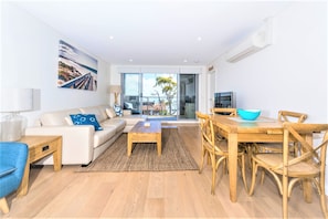 A modern living room with a sofa, coffee table, dining table, and chairs.
