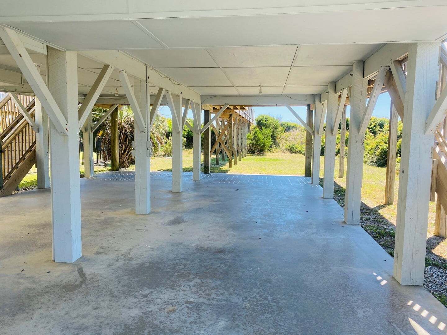 Avoin paviljonki, jossa on betonilattia ja puupalkit.