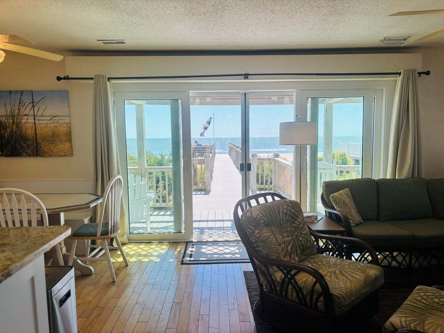 A room with a balcony, a dining area, and a seating area with a view of the ocean.