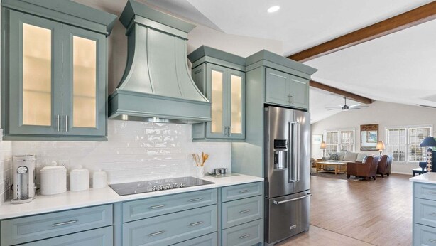 Une cuisine moderne avec des meubles de couleur bleu clair, un réfrigérateur en acier inoxydable et une cuisinière encastrée.