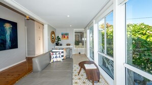 Een moderne woonkamer met een grijze bank, een salontafel en een groot raam met uitzicht op groen.