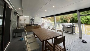 An outdoor patio with a wooden table and chairs, a grill, and a covered seating area. - Victor Parade Pet Friendly Shoal Bay Home (Shoal Bay)