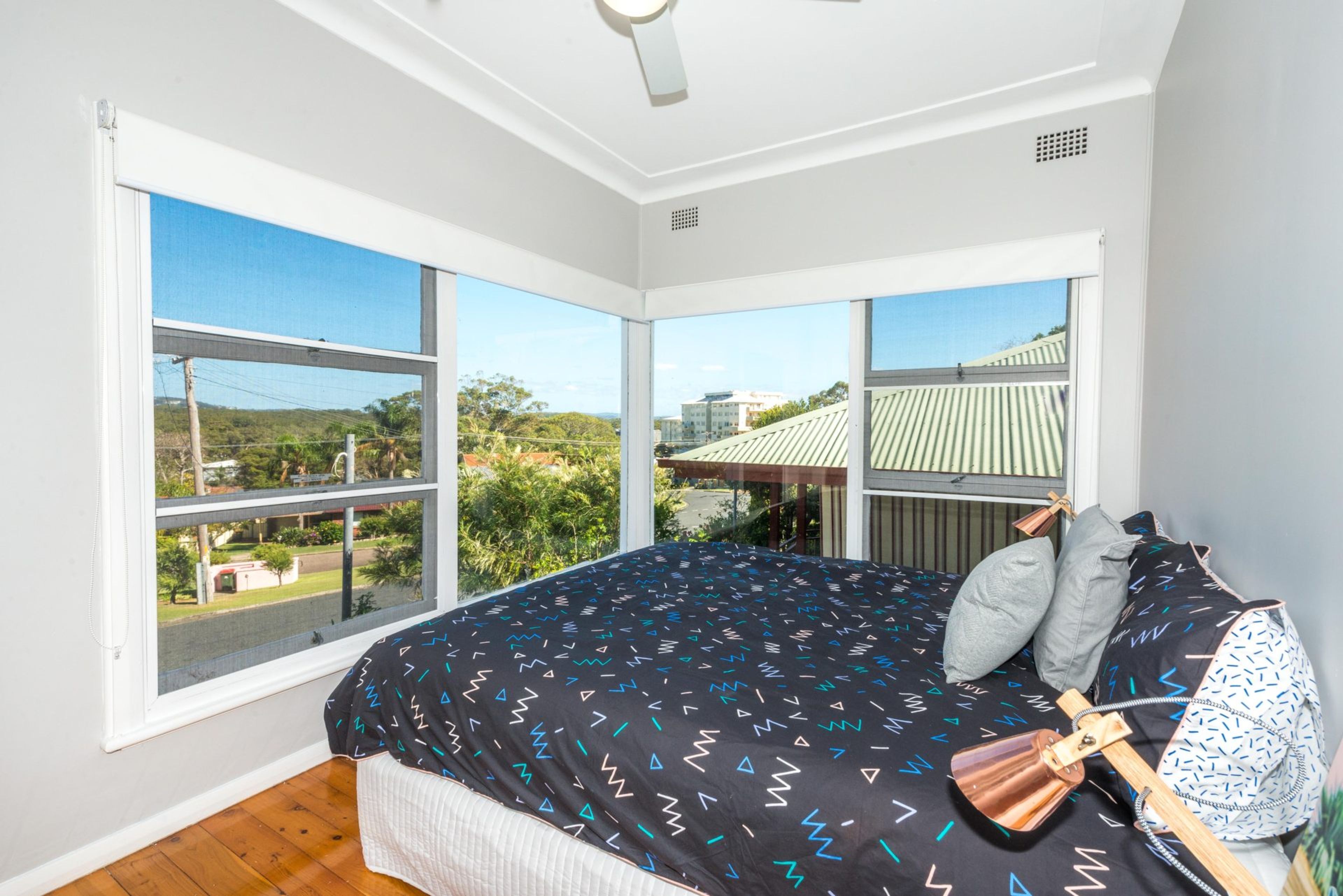Un dormitorio con una cama grande, vistas al exterior y un ventilador de techo.