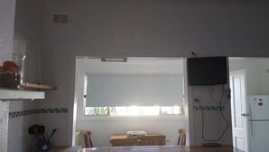 Een keuken met een raam, een aan de muur bevestigde televisie en een koelkast.