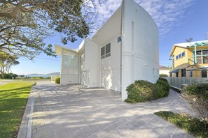 A modern building with a curved facade, large windows, and a paved entrance area.