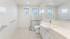 Een moderne badkamer met een glazen douchecabine, een toilet en een wastafel met spiegel erboven.
