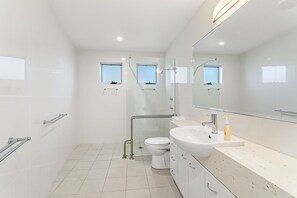 Casa de banho moderna com cabine de duche em vidro, sanita e lavatório com espelho em cima.