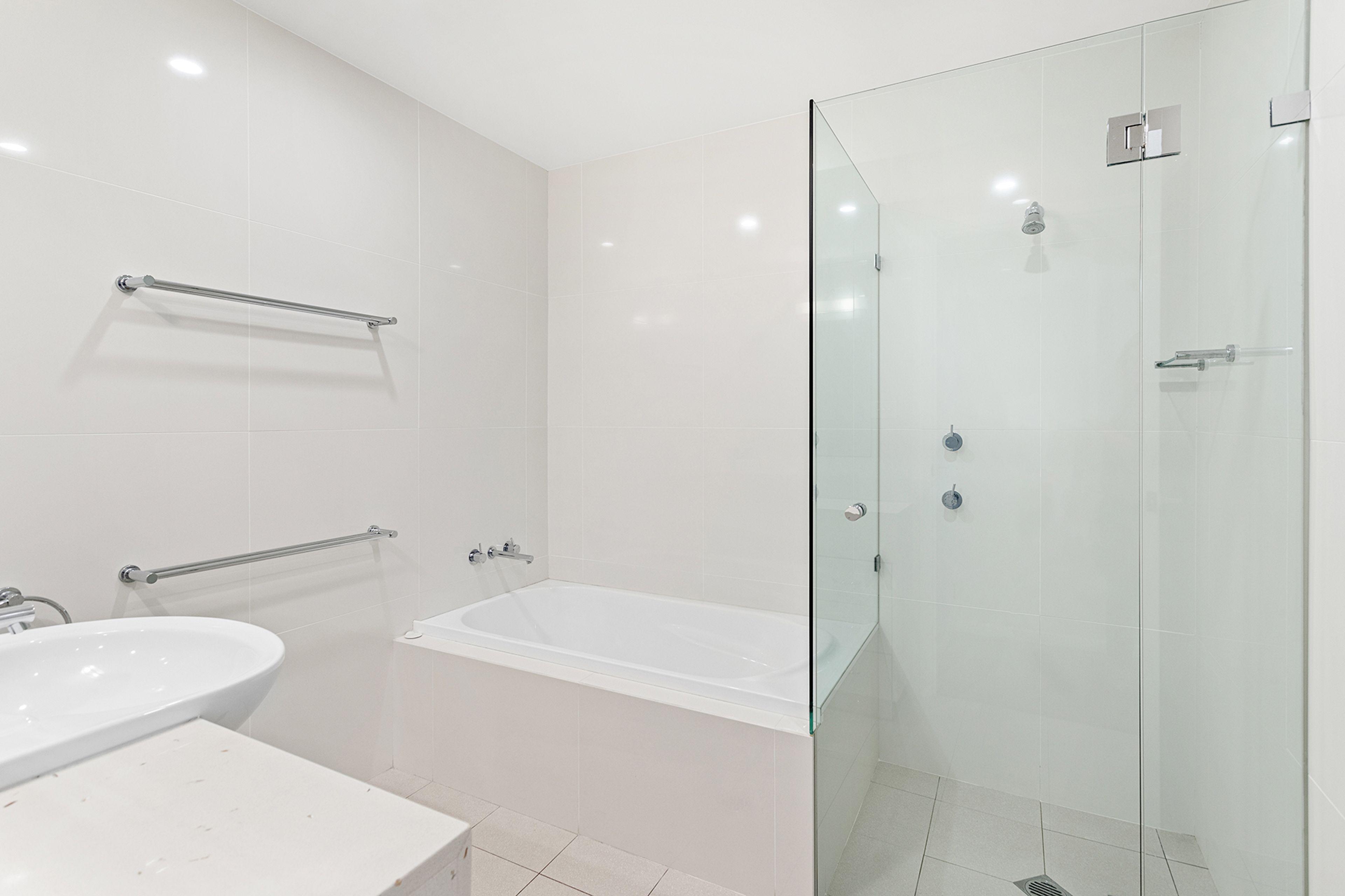 A modern bathroom with a glass-enclosed shower, a bathtub, and a sink.