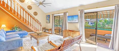A spacious living room with a staircase, a sofa, a coffee table, and a dining area.