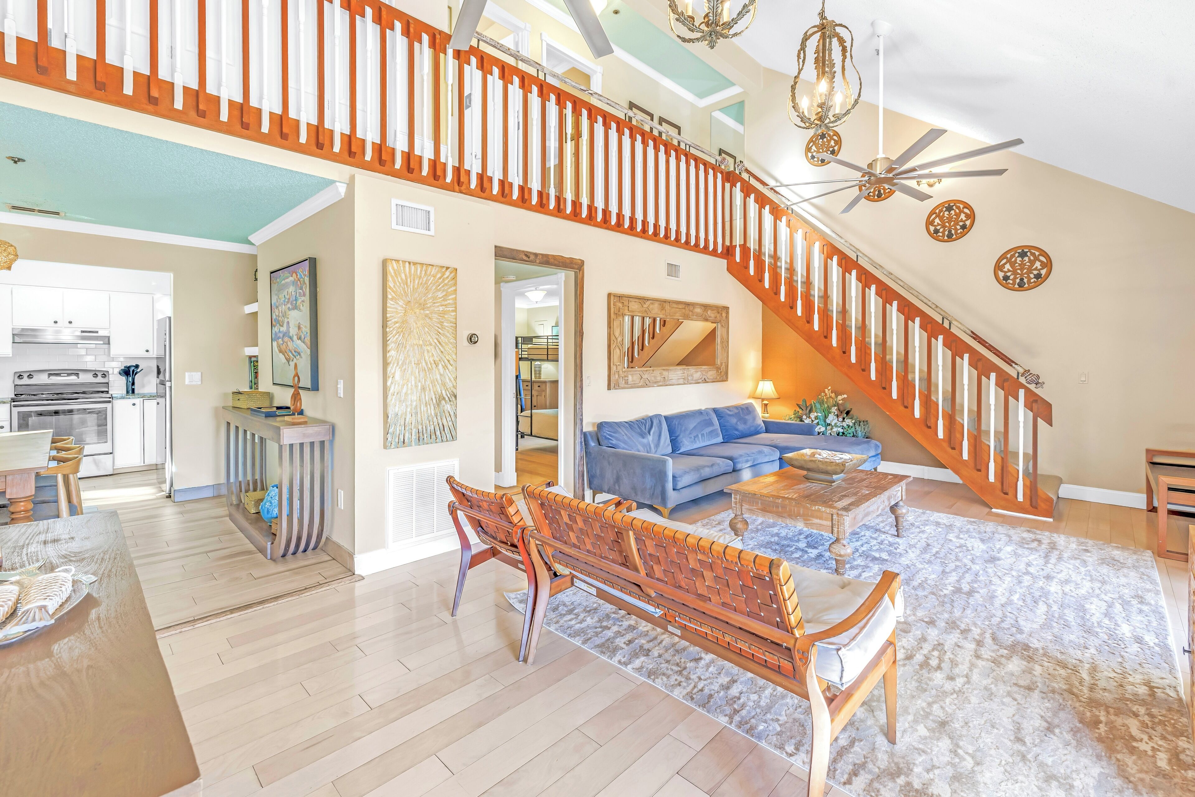 A spacious living area with a wooden bench, a blue sofa, and a staircase with a wooden railing.