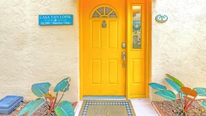 A bright yellow door with a sign above it reading "CASA VAN LOPIK" and a house number sign "360". - Gertrude's Siesta | 4-min Walk to Beach & Village | Balcony & Tropical Patio! (Siesta Key)