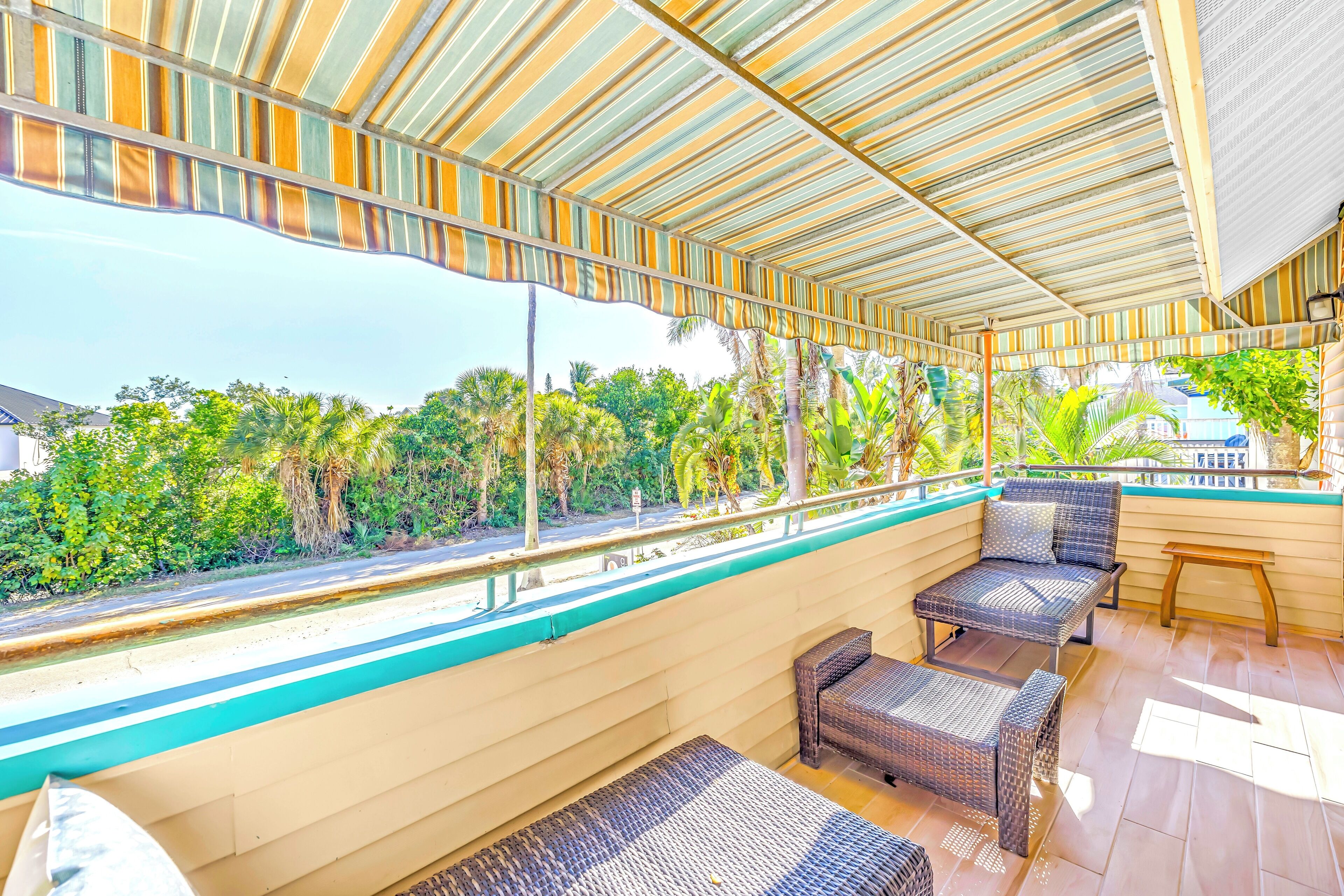 A covered outdoor seating area with wicker furniture and a view of greenery.