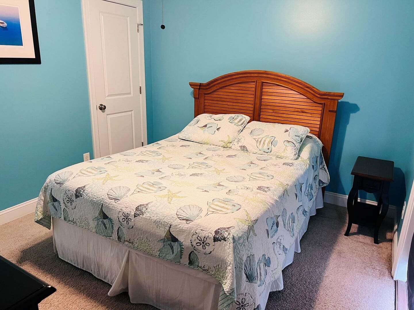 A bedroom with a bed, a door, and a small table.