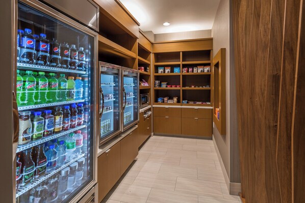 A narrow hallway with vending machines on one side and wooden shelving units on the other.