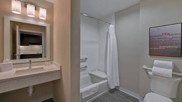 A bathroom with a sink, mirror, shower, and toilet.