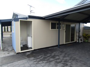 A small, single-room structure with a toilet, a window, and a door. - BLUE LINE UNIT 5 - Great location! close to all amenities! Off Peak Special! (Port Vincent)