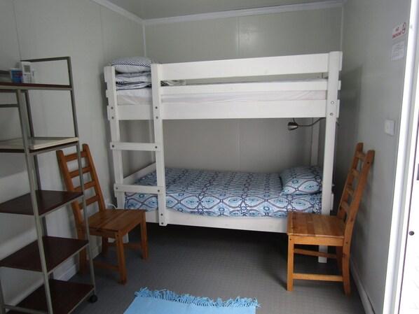 Dormitorio con literas, escritorio, sillas y estante.
