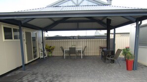 A covered patio area with a brick floor, a table and chairs, and potted plants. - BLUE LINE UNIT 5 - Great location! close to all amenities! Off Peak Special! (Port Vincent)