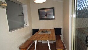 A dining area with a wooden table, benches, and a framed picture on the wall. - BLUE LINE UNIT 5 - Great location! close to all amenities! Off Peak Special! (Port Vincent)
