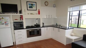 A modern kitchen with white cabinets, a microwave, oven, and a sink. There is a window with a view of the outside. - BLUE LINE UNIT 5 - Great location! close to all amenities! Off Peak Special! (Port Vincent)