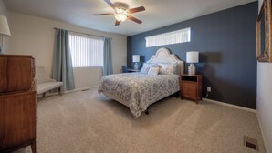 A bedroom with a bed, nightstands, a dresser, a ceiling fan, and a window with curtains. - Quiet home with a view and AC!! (Colorado Springs)