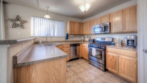 A kitchen with wooden cabinets, stainless steel appliances, a granite countertop, and a star decoration on the wall. - Quiet home with a view and AC!! (Colorado Springs)