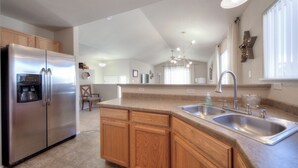 A modern kitchen with a stainless steel refrigerator, wooden cabinets, a double sink, and a chandelier. - Quiet home with a view and AC!! (Colorado Springs)