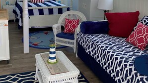 A nautical-themed bedroom with a four-poster bed, a wicker chair, a sofa, and a small table with a lamp. - Waterfront Quiet Retreat, Plymouth, Pet Paradise, Private Beach, Sleeps 4 (Plymouth)