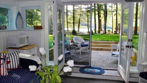 A room with a sliding glass door leading to a patio with outdoor furniture and a view of trees. - Waterfront Quiet Retreat, Plymouth, Pet Paradise, Private Beach, Sleeps 4 (Plymouth)