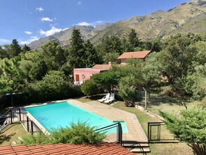 A swimming pool surrounded by greenery and a mountain backdrop. - Chalet Paseo del Zorzal (Merlo)