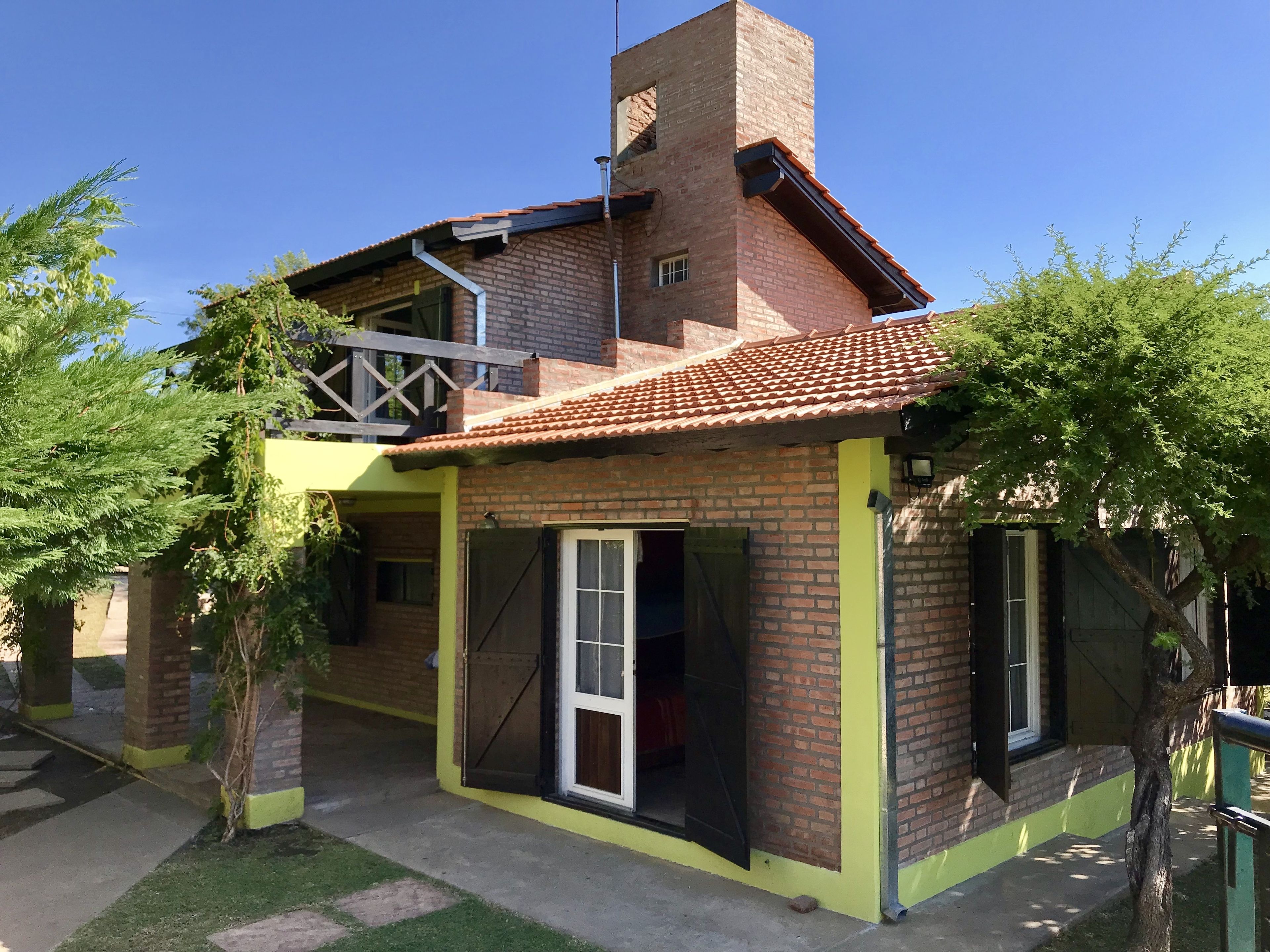 Une maison à deux étages, avec une façade en briques et un toit recouvert de tuiles.