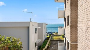 Una calle estrecha con vista al mar, un coche aparcado y un edificio con balcón.