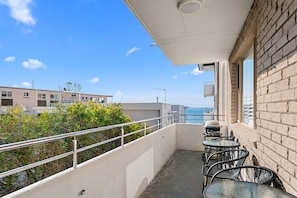A balcony with a table and chairs, overlooking a body of water and buildings.